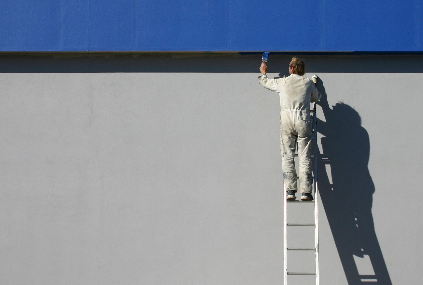 Pintor trabajando sobre una escalera en una pared exterior