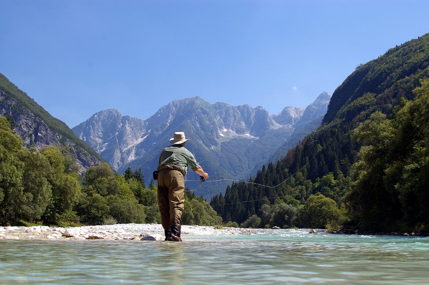 Pescador con mosca en un río de montaña